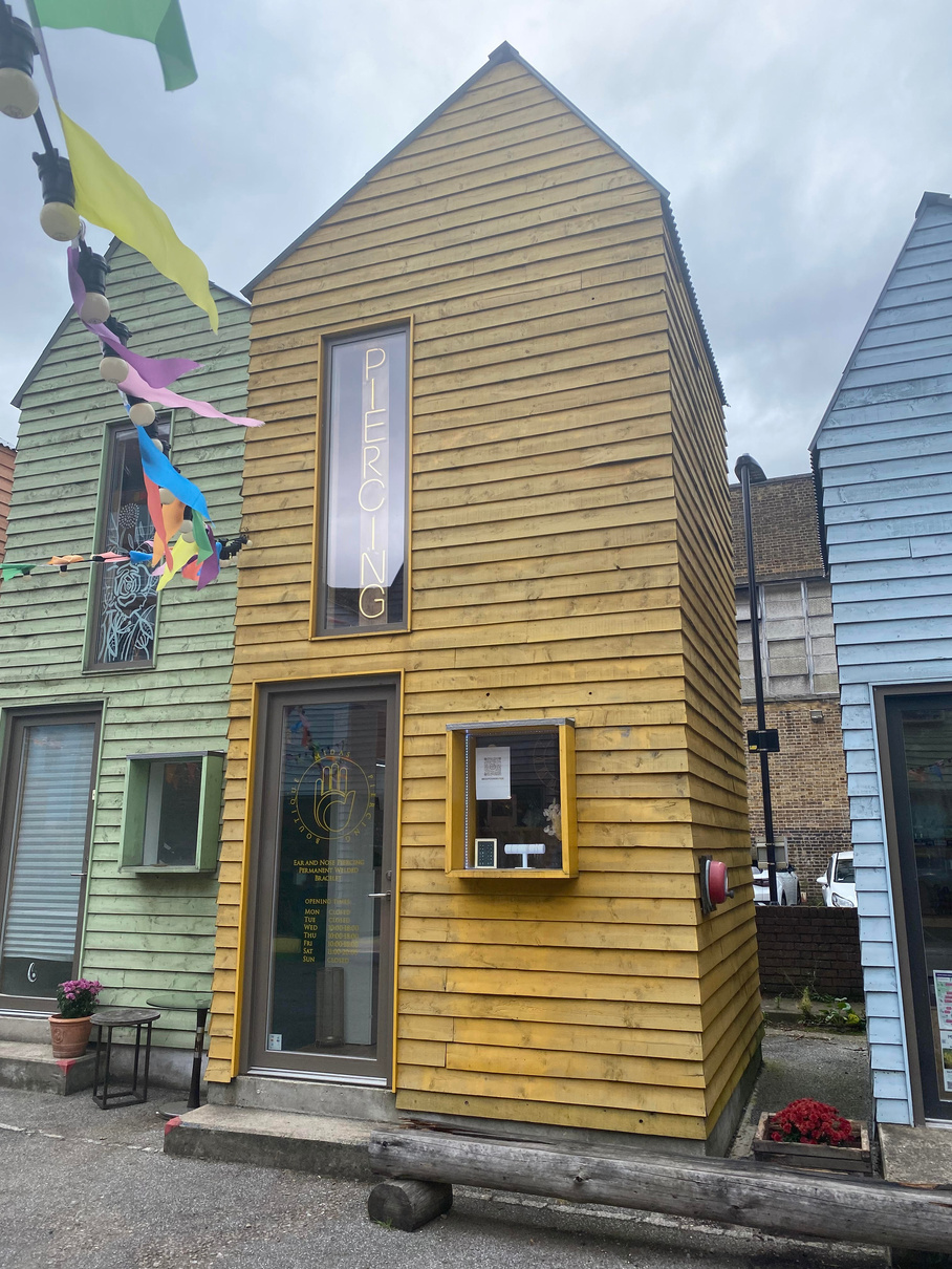 a building that is painted yellow and has a piercing sign on it